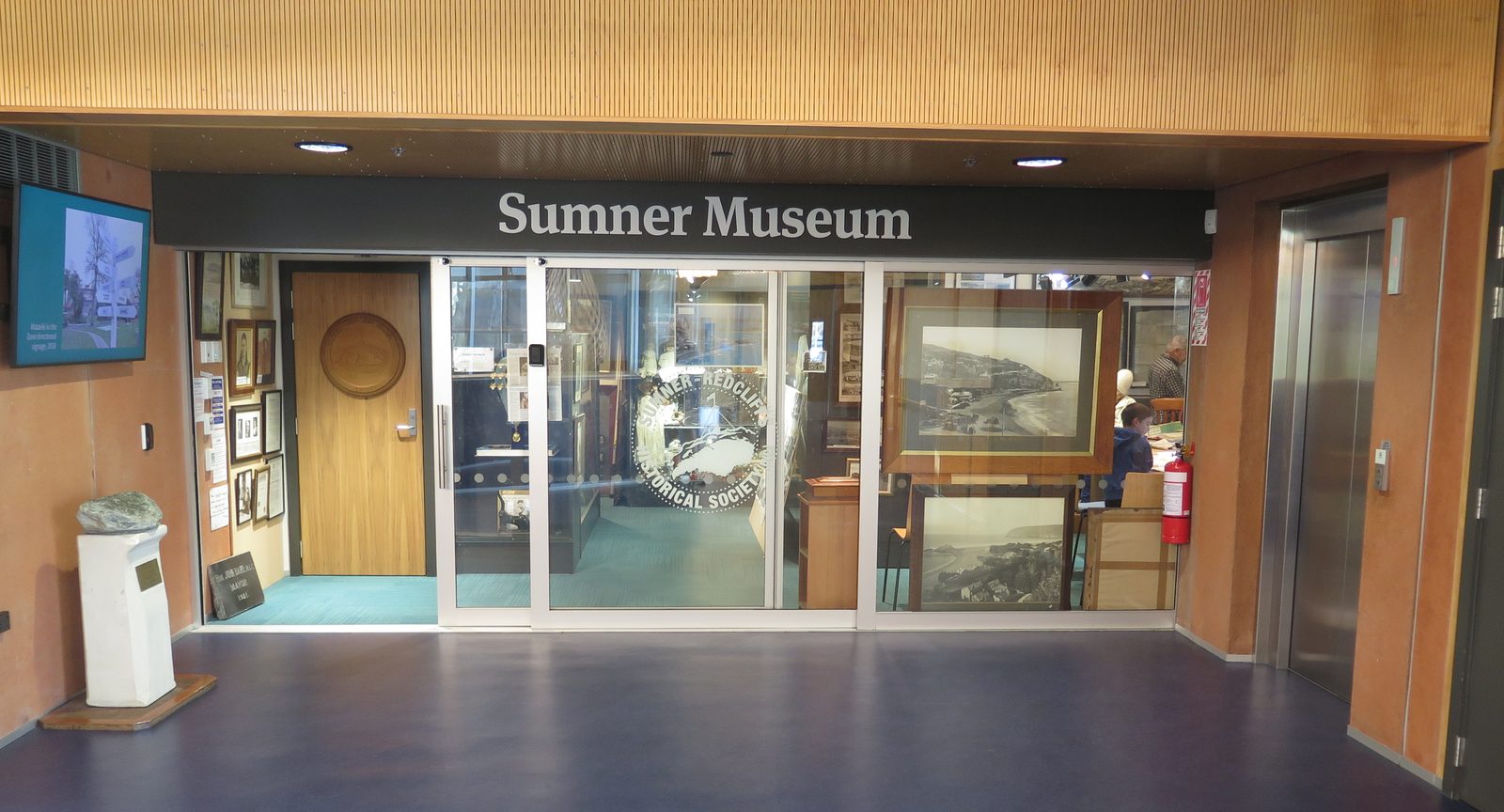 The Sumner Museum entrance inside Matuku Takotako: Sumner Centre, with the society's seal on the glass doors