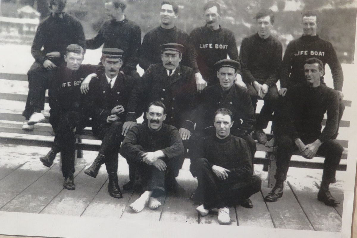 Black and white photograph of the Sumner lifeboat crew in Life Boat jerseys, seated on a bench