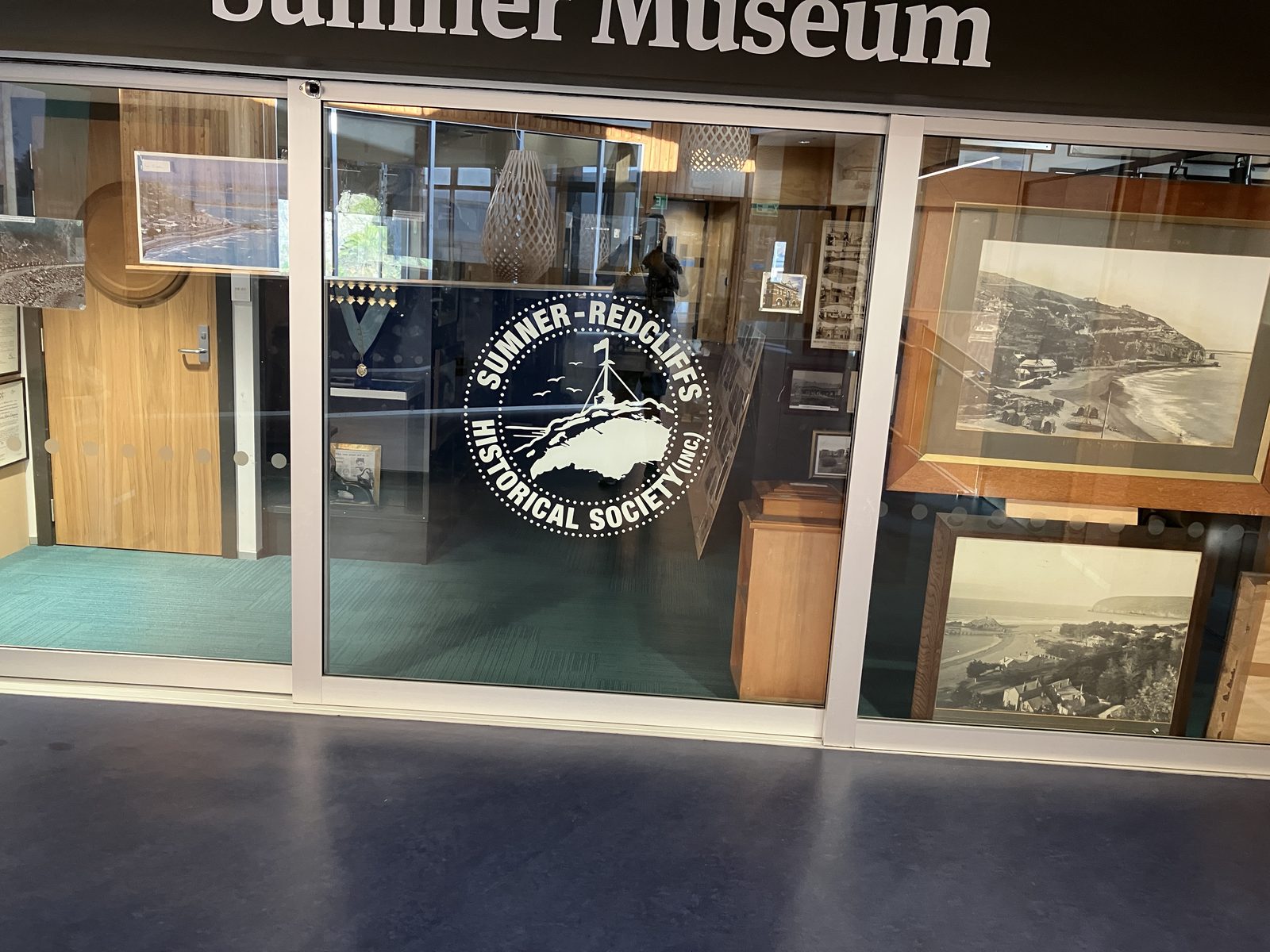 The glass entrance of the Sumner Museum with the society seal, inside Matuku Takotako